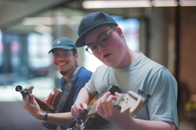 Guitar instructor smiling while student guitarist plays